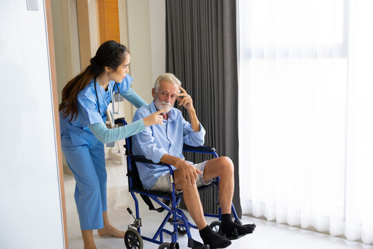 Female Nurse assisting senior patient at nursing home. Home care. disabled old man with walker at home. Professional caregiver nursing home