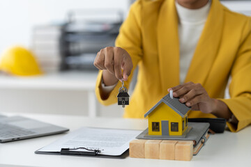Real estate agent, african american businesswoman holding house model and keys with contract...