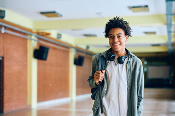 Happy black teenage boy in school hallway looking at camera. - obrazy, fototapety, plakaty