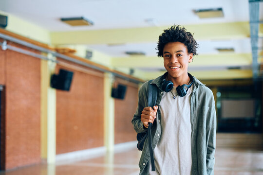 Happy black teenage boy in school hallway looking at camera.