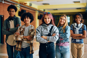 Multiracial group of confident teenagers in high school hallway looking at camera.