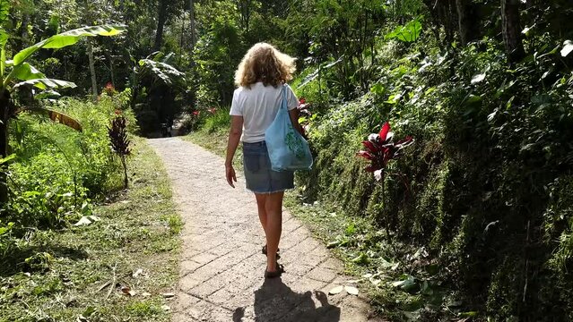 Bali, Indonesia A woman tourist walks a path in the jungle, 