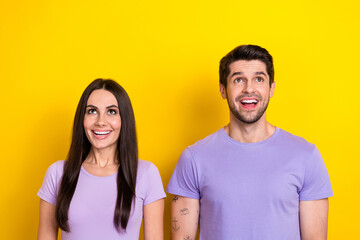Fototapeta premium Portrait of astonished positive partners open mouth look up above empty space isolated on yellow color background