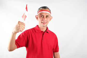 Portrait of Asian Man holding red and white Indonesia flag attribute. Independence day concept.
