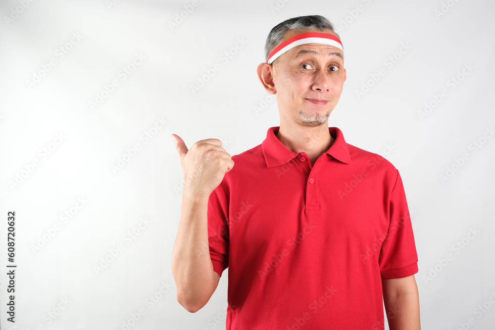 Wall mural Portrait of Asian Man wearing red and white Indonesia flag attribute looks happy doing positive gesture with thumbs up, smiling
