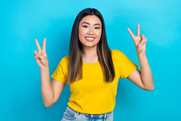 Portrait pretty asian beauty girl show v sign gesture hands friendly person wear yellow t-shirt isolated blue teal color background