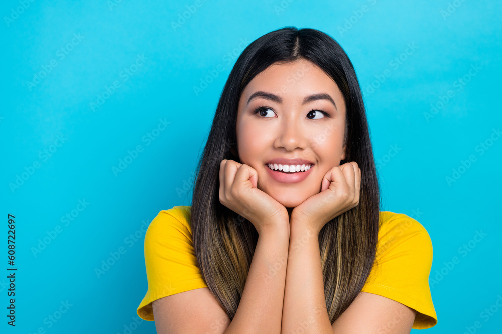 Wall mural Portrait of good mood woman with dyed hairstyle wear stylish t-shirt hands under chin look empty space isolated on blue color background