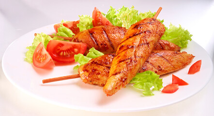 Haehnchenspiesse mit Salatbeilage auf einem weissen Teller