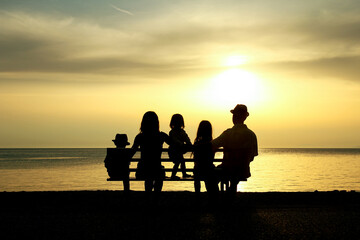 Naklejka na ściany i meble A happy family in nature by the sea on a trip silhouette