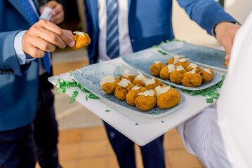 Unrecognizable men taking potato croquettes during banquet