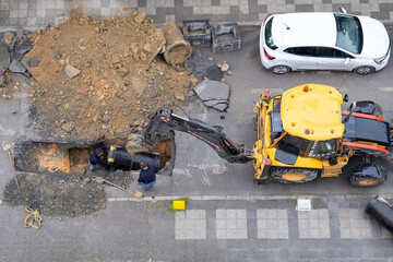 An excavator repairs sewer storm hatches ata street on a summer day. Selective Focus Machine. Top View.