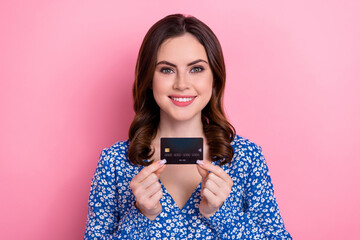 Photo of optimistic adorable cute woman wavy hairdo wear blue dress hands hold credit plastic card isolated on pink color background