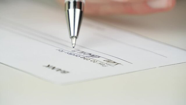 The pen writes in close-up, fills out the form of a check for the amount. A businessman writes a check. Business concept, money turnover, banking