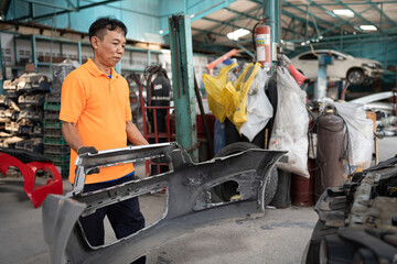 Fototapeta na wymiar Asia auto mechanic repair car body bumper replacement with car lift background at car service