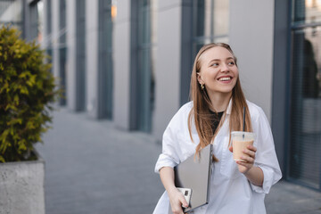 Beautiful woman going to work with ice latte walking near office building. Successful business...