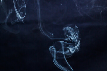 Smoke curls up from incense on a blue background	
