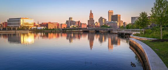 Providence downtown skyline, buildings, and curving riverbank trail at sunrise, tranquil water...