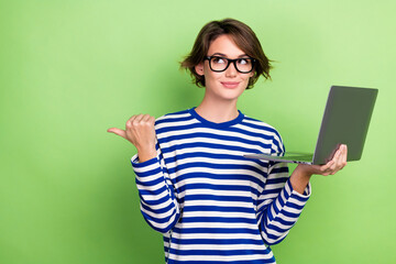 Photo of satisfied girl short haircut dressed sailor long sleeve look directing at sale hold laptop isolated on green color background