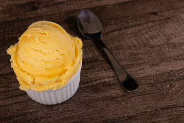Vanilla ice cream served in a white bowl next to a spoon. Gourmet photograph of frozen desserts with empty space to the right of the image.