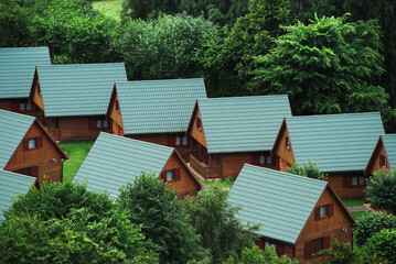 View of symmetrically arranged houses. Roofs protruding above green plants. 