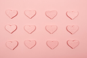 Pink color wooden hearts pattern isolated on the bright solid pink fond background