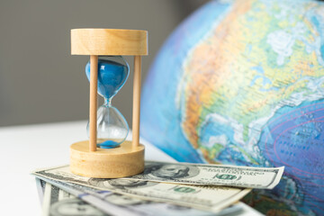 Wooden egg timer alongside a world globe or earth in a concept of running out of time to save the planet from pollution and destruction of the ecology