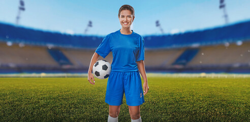  Portrait of young female soccer player with soccer ball standing in a stadium.
