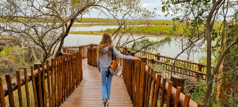girl walking on wooden bridge in the middle of the african savannah