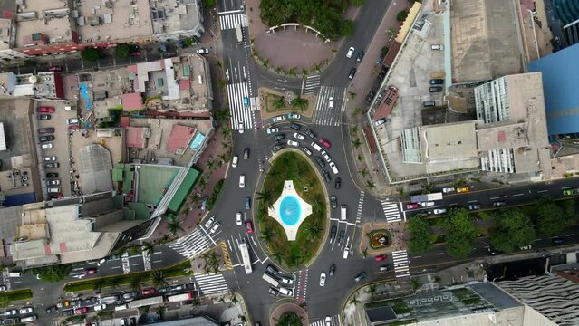 Aerial shot drone descends on blue traffic roundabout at end of central park in downtown