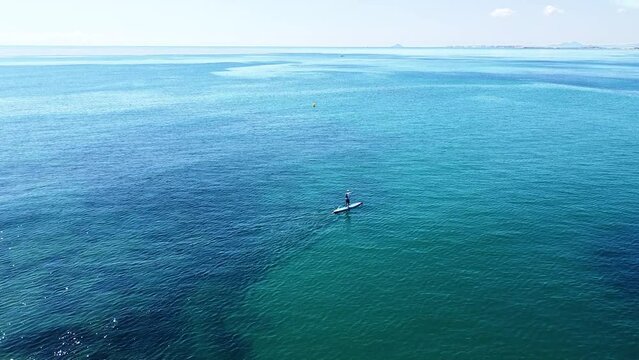 Aerial view of sportsman praciticing standup paddleboarding