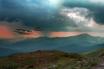 UFO, space saucer flying in the sky over high mountains. Landscape with an invasion by an extraterrestrial space object in summer