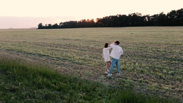 couple in love in white clothes on a date in a field at sunset. Concept of love, engagement and wedding