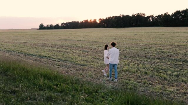 couple in love in white clothes on a date in a field at sunset. Concept of love, engagement and wedding