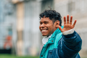 young latino man waving in the street