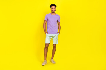 Full body size cadre of young smiling happy man student summer outfit model blue shorts violet t-shirt isolated on yellow color background