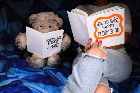 Young woman sits on the couch with Teddy Bear and reads books. Charming, raising concept, spending time together, and communication.