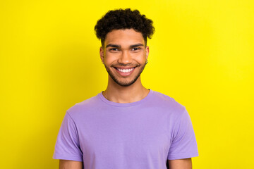 Photo of cheerful positive guy dressed purple t-shirt smiling showing white teeth isolated yellow...