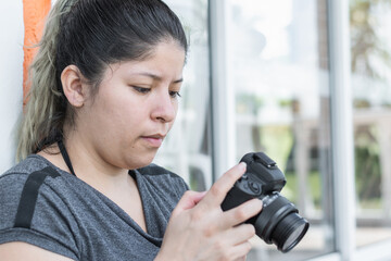 close-up of a young latina woman looking at the videos she recorded for her networks on her camera.
