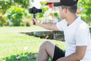 Rear view of a young Latino male blogger capturing authentic self-portraits with a handheld camera, adding an engaging personal touch to his content creation.