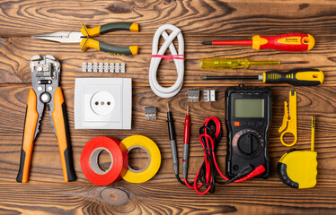 Electrician equipment on brown background with copy space.Top view.Electrician tool set.Multimeter, tester,screwdrivers,cutters,duct tape,lamps,tape measure and wires.Flet lay. © Avocado_studio