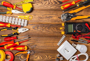 Electrician equipment on brown background with copy space.Top view.Electrician tool set.Multimeter, tester,screwdrivers,cutters,duct tape,lamps,tape measure and wires.Flet lay. © Avocado_studio