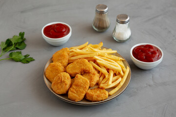 Homemade Chicken Nuggets and French Fries with Ketchup on gray background, side view.