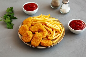 Homemade Chicken Nuggets and French Fries with Ketchup on gray background, side view.