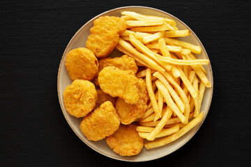 Homemade Chicken Nuggets and French Fries with Ketchup on black background, top view. Flat lay, overhead, from above.