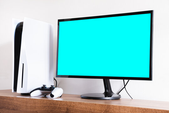 White video game console next to controller of the same color connect to 24-inch screen