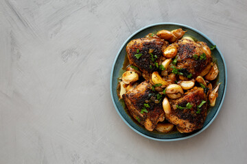 Homemade Chicken With 40 Cloves of Garlic on a Plate, top view. Flat lay, overhead, from above. Copy space.