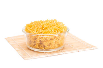 Uncooked Fusilli Pasta in Glass Jar on Bamboo Mat Isolated on White Background. Fat and Unhealthy Food. Classic Dry Spiral Macaroni. Italian Culture and Cuisine. Raw Pasta