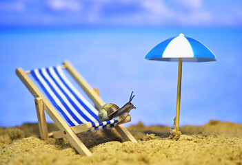 Fototapeta na wymiar snail on the beach. deck chair on the seashore. conceptual macro photo on the theme of vacation