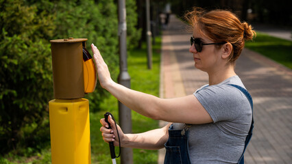 Blind woman pressing a button for a traffic light. 