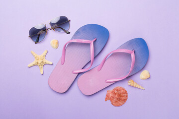 Flip flops with sunglasses and airplane on color background, top view